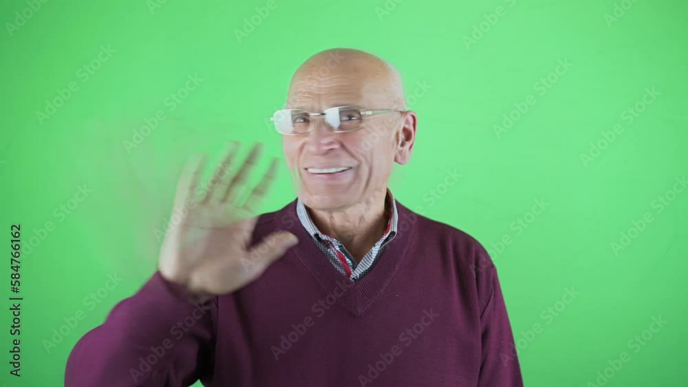 Senior man declines offer with smiling and delighted expression against chromakey wall in studio. Elderly demonstrates positive emotions Senior man declines offer with smiling and delighted expression against chromakey wall in studio. Elderly demonstrates positive emotions