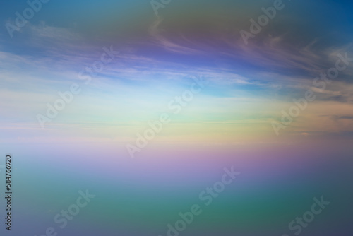 Blurred abstract rainbow background. White clouds on blue sky above the sea © amovitania