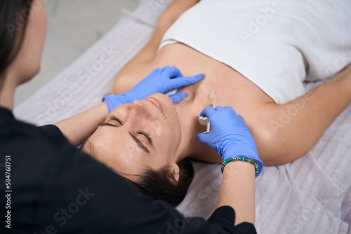 Medic doing injections in salon to pretty lady