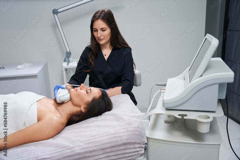 Beautician doing facial skin rejuvenation procedure for young female Beautician doing facial skin rejuvenation procedure for young female