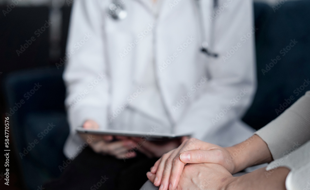 Doctor and patient sitting at sofa in clinic office. The focus is on female woman's hands, close up. Medicine concept