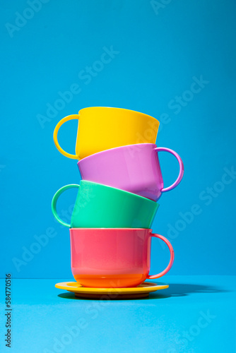 Multicolored ceramic cups on blue background photo