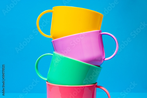 Multicolored ceramic cups on blue background