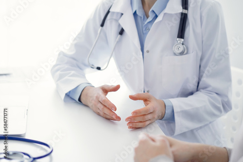 Doctor and patient discussing current health questions while sitting at the table in clinic office, only hands closeup. Medicine concept