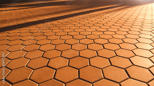 Background and Texture of Geometric Hexagon Brown Cobblestone Pavement in vintage style with Golden Sunlight Reflection and Shadow on Surface