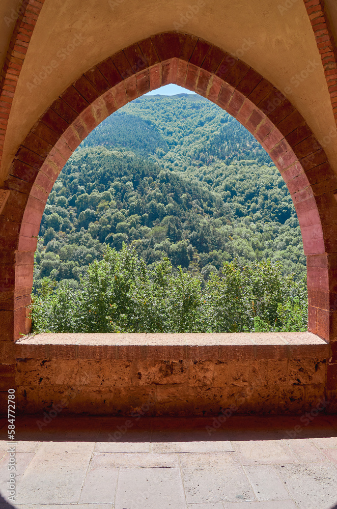 window in the vaults of a mountain abbey with green forest in the background