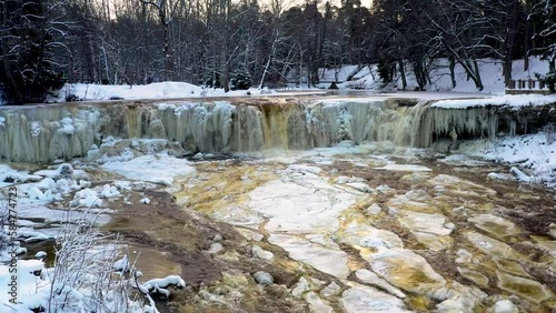 Golden water flows from a frozen winter waterfall. Keila Joa, Estonia. photo