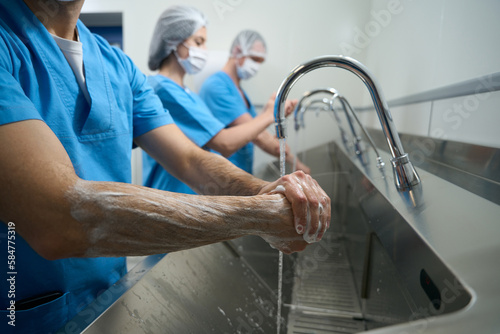 Team of surgeons thoroughly washes their hands before surgery
