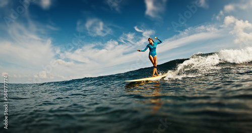 Slim woman surfer rides the wave. Woman surfs the ocean wave in the Maldives on yellow longboard