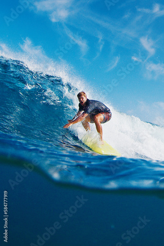 Surfer rides the wave. Exited man surfs the ocean wave in the Maldives, splitted underwater view