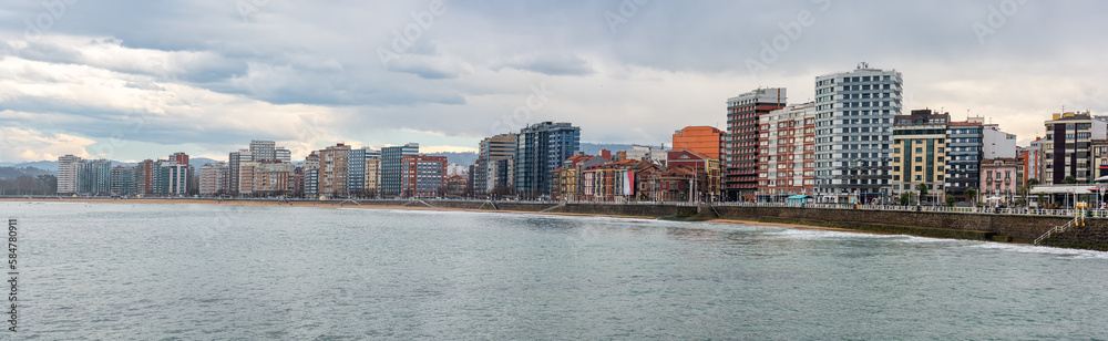 Panoramic view of the city of Gijon with tall buildings by the edge of the sea on the beach of San Lorenzo, Spain.