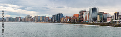 Panoramic view of the city of Gijon with tall buildings by the edge of the sea on the beach of San Lorenzo, Spain.