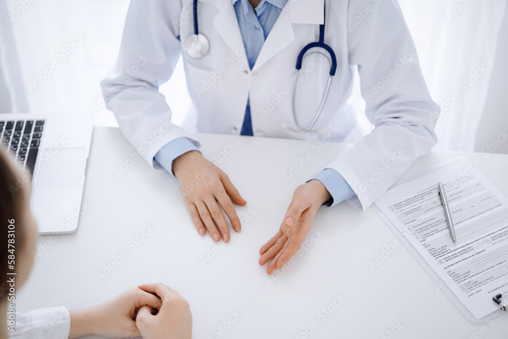 Doctor and patient discussing current health questions while sitting opposite of each other at the table in clinic, close up and above view. Medicine concept Doctor and patient discussing current health questions while sitting opposite of each other at the table in clinic, close up and above view. Medicine concept