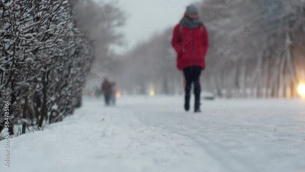 Urban female pedestrian in a snowfall blizzard on a city street in cold winter weather Urban female pedestrian in a snowfall blizzard on a city street in cold winter weather