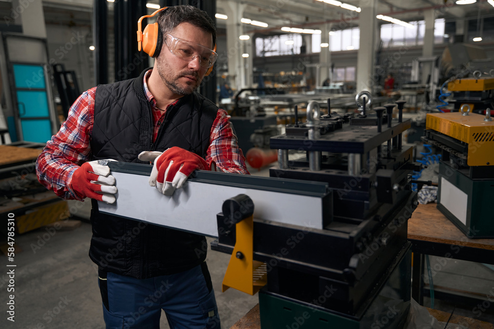 Adult male working with steel profile on the equipment