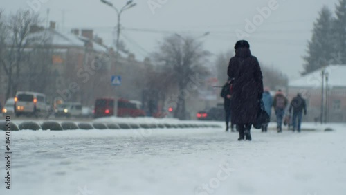 Urban people pedestrians and car traffic in a snowfall blizzard on a city street in cold windy winter Christmas weather 