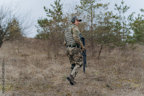 a soldier walks through the forest with a machine gun. a military man in full-length camouflage