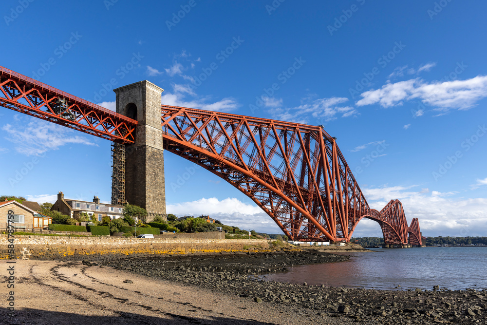 Obraz premium The mighty Forth rail bridge spreading across the Firth of Forth connecting north and south Queensferry. Taken from North Queensferry on A bright summer's day.
