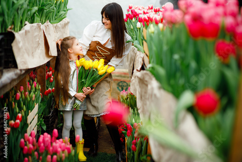 Mother and daughter among thousands of bright tulips. Growing and caring for flowers