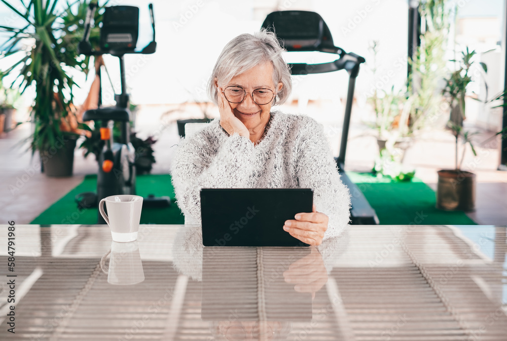 Senior attractive woman using digital tablet sitting outdoor, smiling grey-haired woman looking on web pages Senior attractive woman using digital tablet sitting outdoor, smiling grey-haired woman looking on web pages