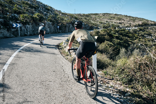 Two cyclists training on Vall d'Ebo pass.Cycling in the spanish mountains.Cyclists in helmets and cycling wear conquer Vall d'Ebo pass.Sport motivation.Cycling professional group ride.Beautiful view.