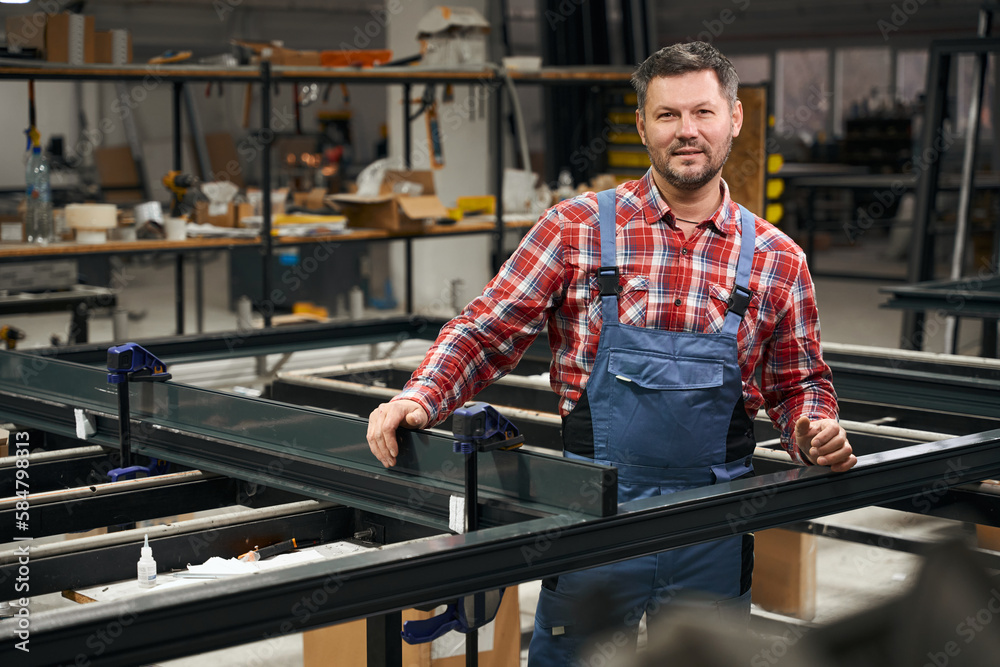 Obraz premium Portrait of man connecting metal parts in factory