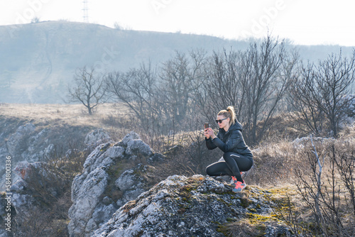 Sporty young blonde woman photographing landscape with mobile phone photo