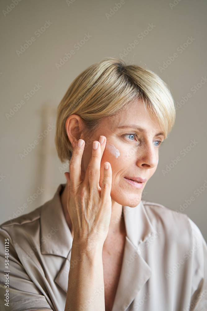 Mature woman applying cream on face Mature woman applying cream on face