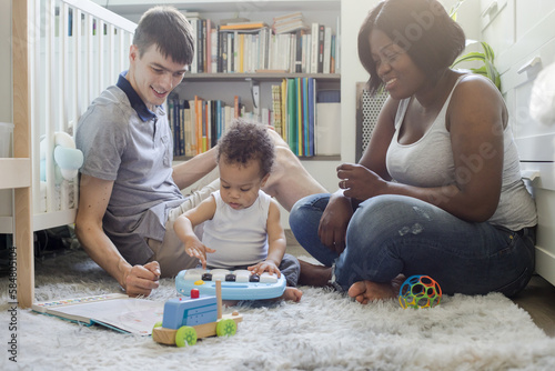 parents with toddler baby child playing with toys at home, toy piano photo