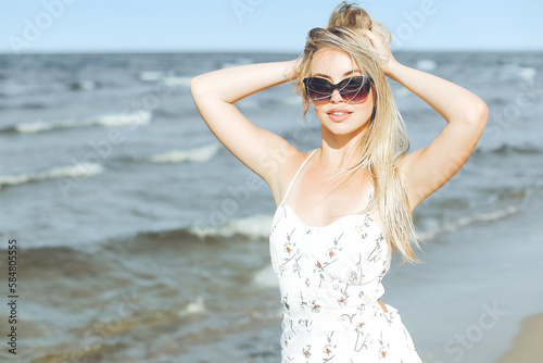 Happy blonde woman in free happiness bliss on ocean beach standing with sun glasses © rogerphoto