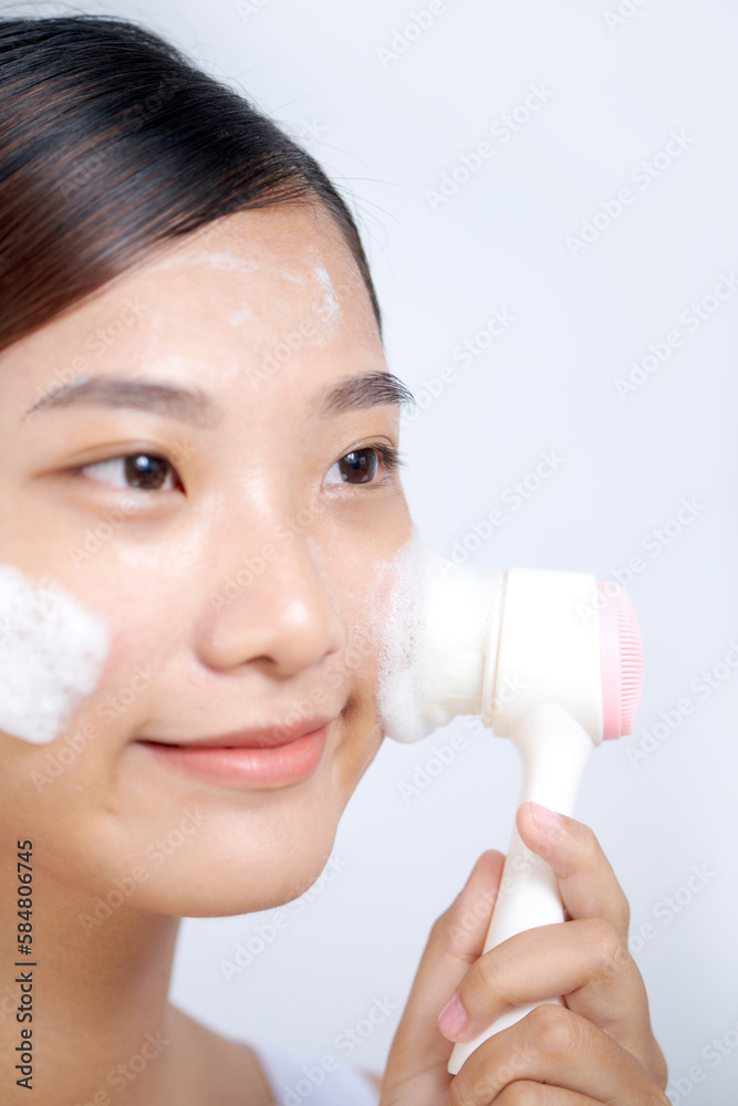 Young woman washing face with brush and cleansing foam on face Young woman washing face with brush and cleansing foam on face