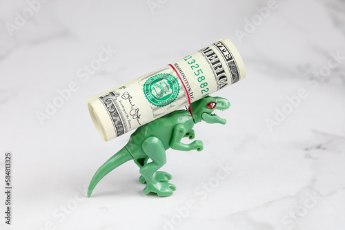 Small green dinosaur carries roll dollar on his back, rope strangles his neck