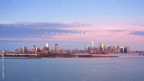Aerial footage of New York City and Jersey City skylines together with Ellis Island, as viewed from above Liberty State Park, in New Jersey, at dusk, with slow camera take-off photo
