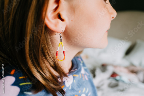 Closeup portrait of a young girl showing her beaded earrings