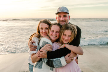 Smiling family hugging at the beach