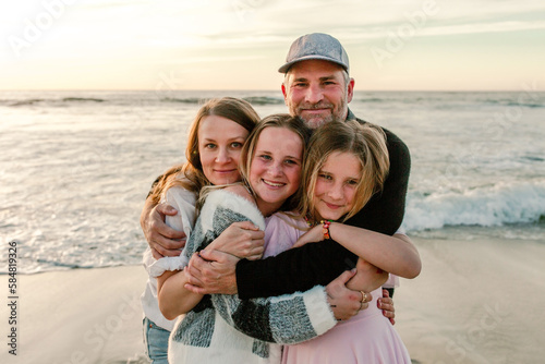 Smiling family hugging at the beach
