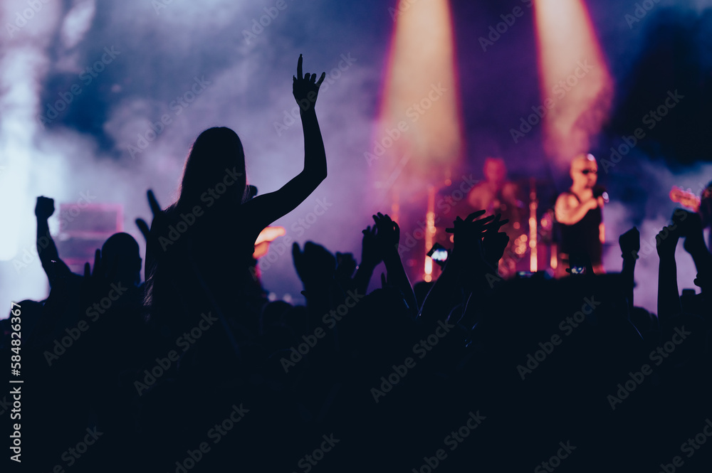 Silhouette of a woman with raised hands on a concert