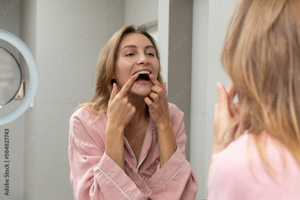 Woman correcting dental aligner in front of mirror