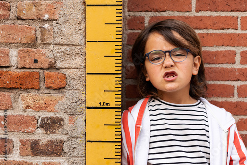 young boy standing beside ruler