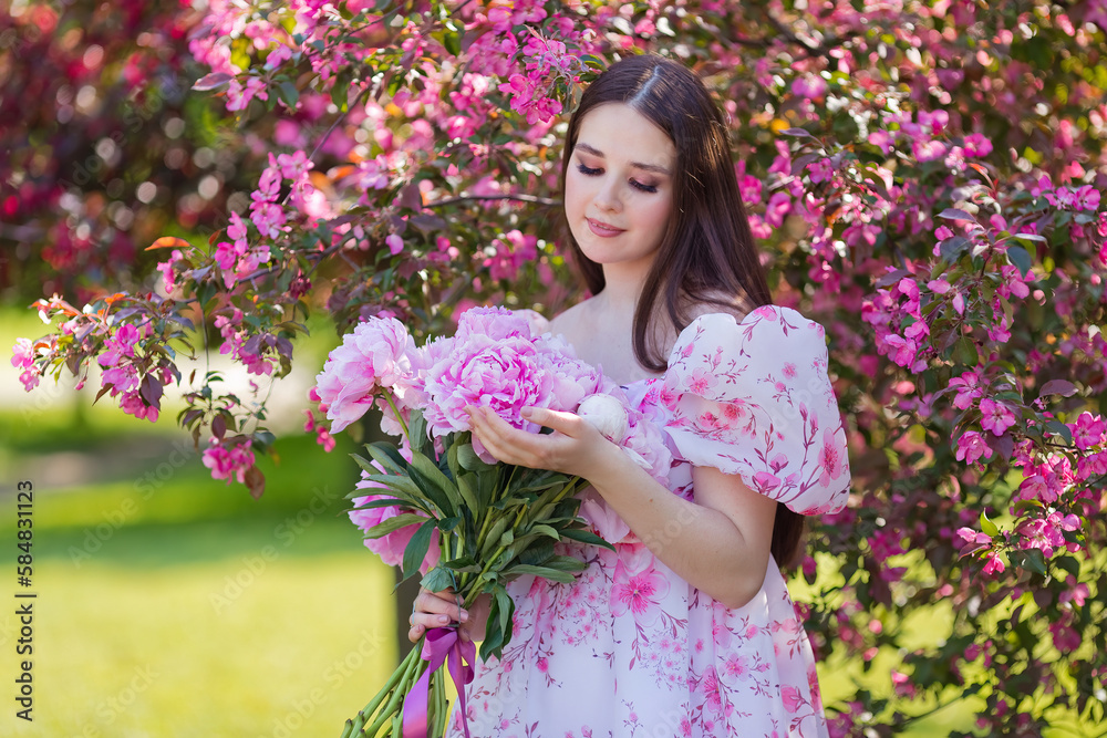 A pretty girl in a dress, with a large bouquet of peonies in garden A pretty girl in a dress, with a large bouquet of peonies in garden