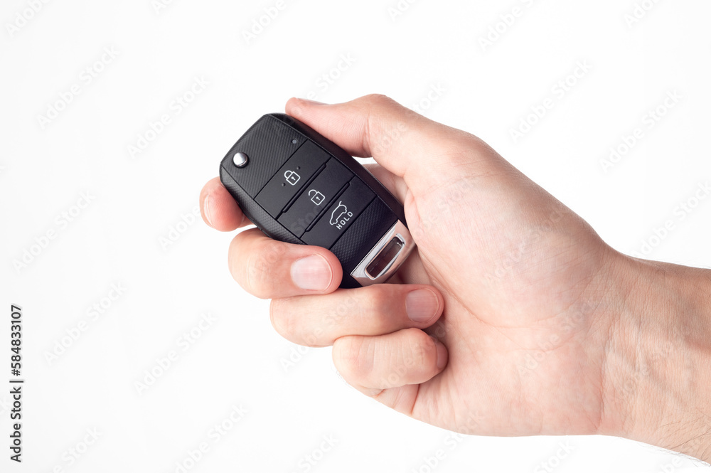 A man's hand holds the car key isolated on a white background close up. A man's hand holds the car key isolated on a white background close up.