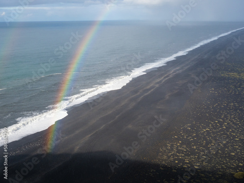 Rainbow at Solheimafjara black sand beach in Vik, Iceland photo