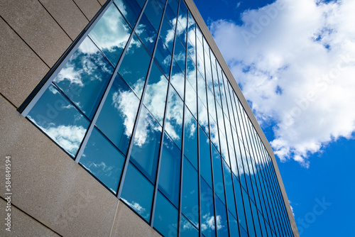 Abstract or graphic photo of the sky with clouds seeming to continue into a building with reflective squares of glass. photo