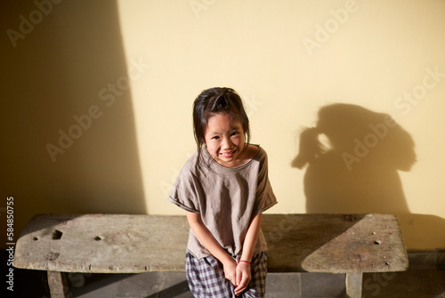 Asian girl resting on a bench in the aisle under sunlight photo