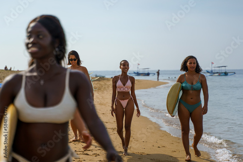 Group of women walking away with surfboards at beach