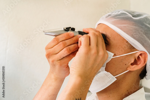 Man looking through a refractometer photo