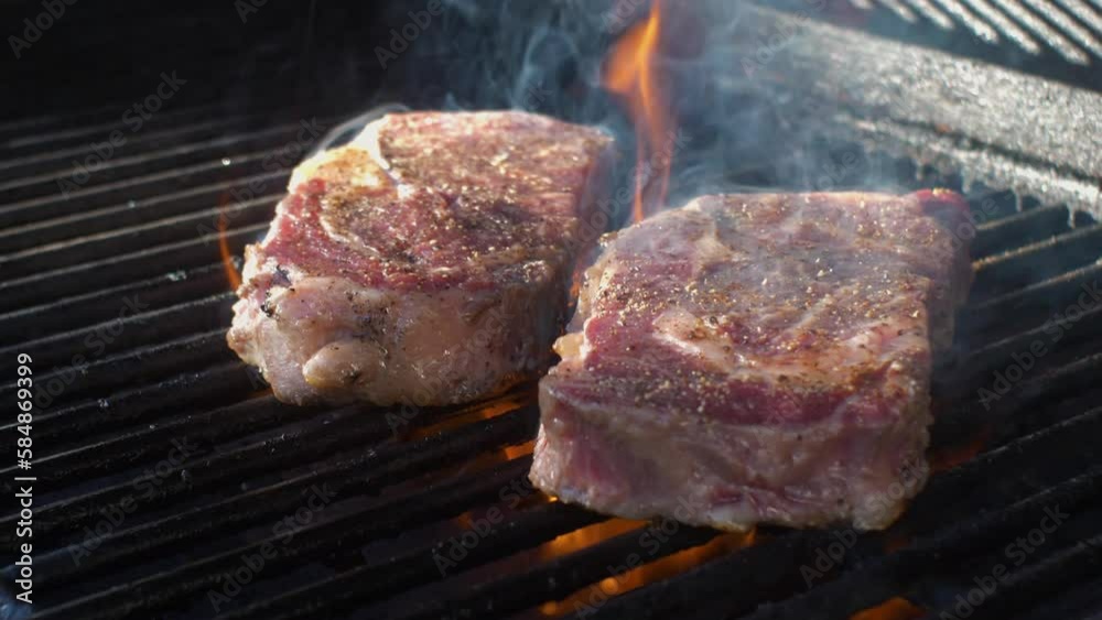 slow motion of two ribeye steaks on a hot barbecue grill slow motion of two ribeye steaks on a hot barbecue grill