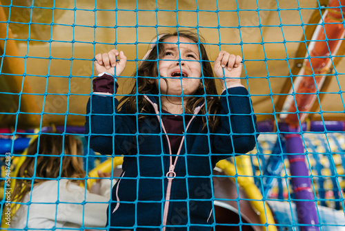 Girl crying behind net on playground