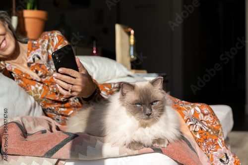 Mature woman using phone with cat at home