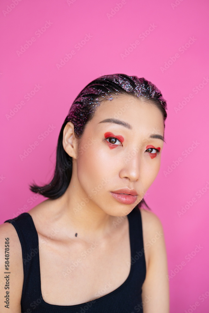 Woman with painted red heart on eyes and glitter on hair Woman with painted red heart on eyes and glitter on hair